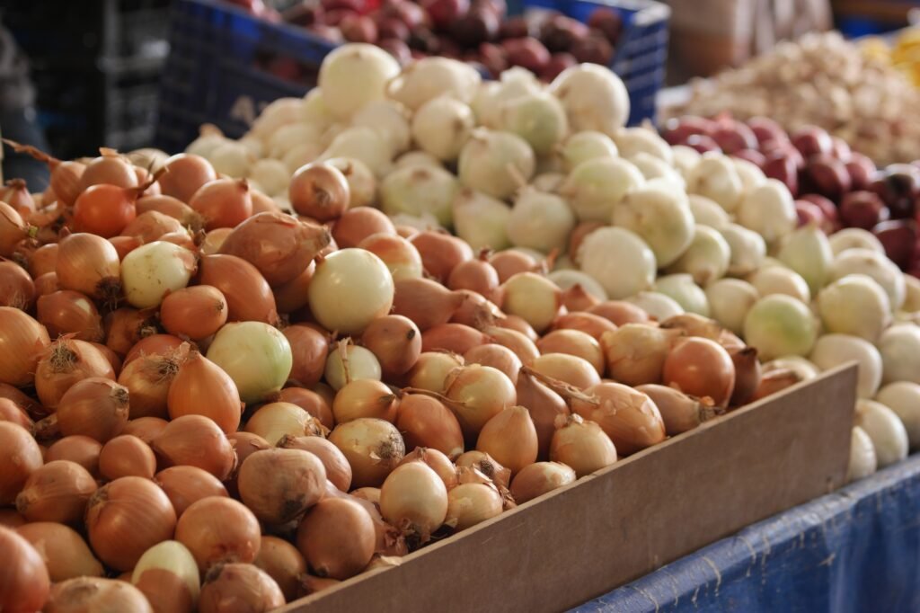 Golden and white onions at market stall.