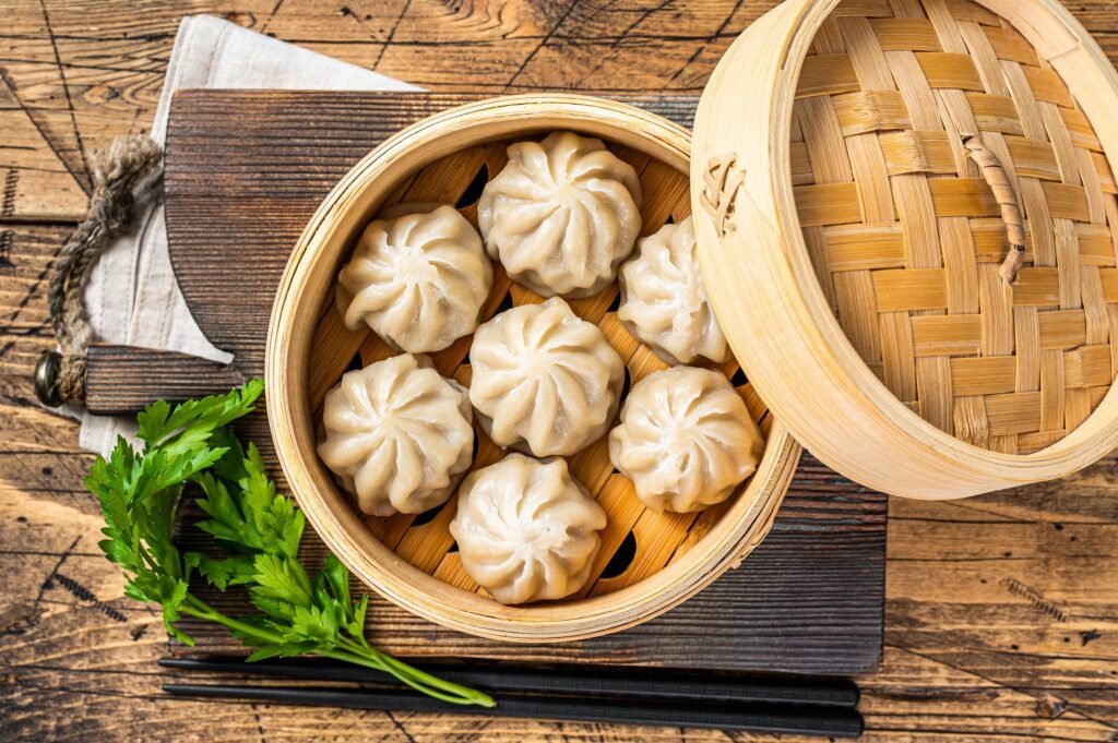 Momo dumplings in a bamboo steamer. Wooden background. Top view